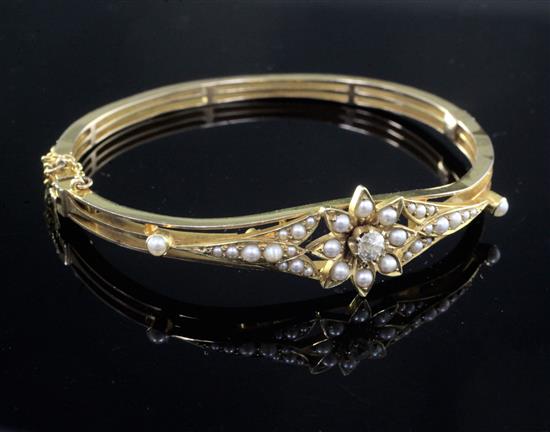 A late Victorian high carat gold, diamond and seed pearl set hinged bangle,